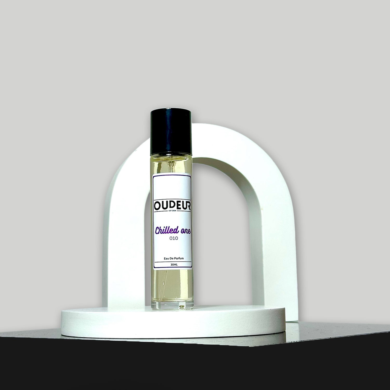 A bottle of '010 - Inspired by Creed Aventus' cologne on a white stand against a grey background.