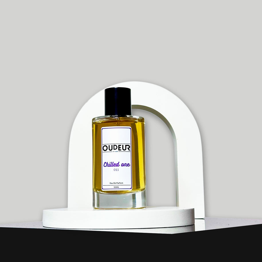 A bottle of perfume labeled 'OUDERIA Chilled air' placed inside a white curved structure, with a dark background.