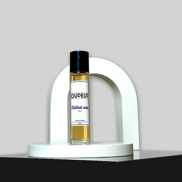 A bottle of perfume labeled 'OUDERIA Chilled air' placed inside a white curved structure, with a dark background.