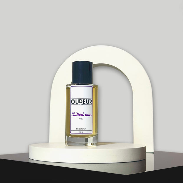 A bottle of perfume labeled 'OUDERIA Chilled air' placed inside a white curved structure, with a dark background.