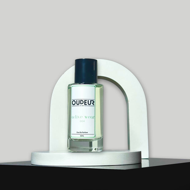 A bottle of Oudeis cologne displayed within a white, curved structure on a grey background.