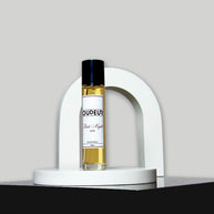 A bottle of perfume with a vibrant red label, displayed in front of a white arch-shaped stand against a grey background.