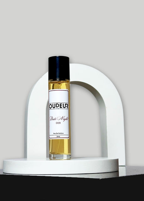 A bottle of perfume with a vibrant red label, displayed in front of a white arch-shaped stand against a grey background.