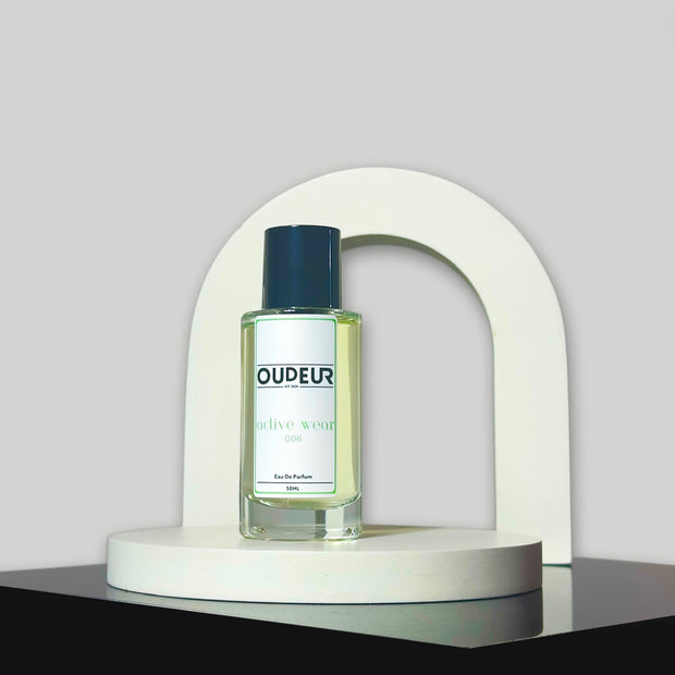 A bottle of perfume labeled 'DUPEUS' placed under a white arch on a grey background, representing the product '006 - Inspired by MFK Gentle Fluidity'.