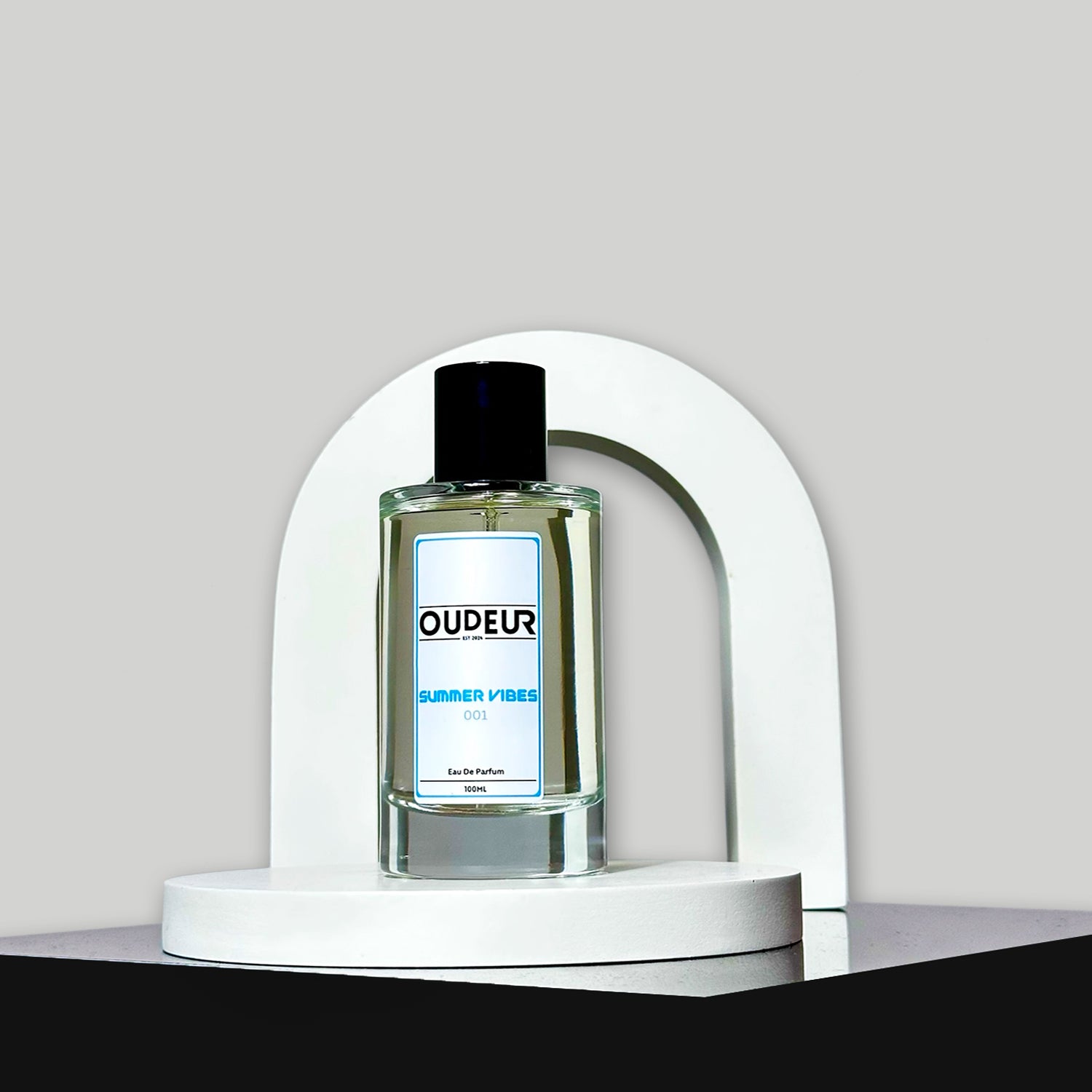 A bottle of perfume displayed on a white stand with a curved top, the liquid is clear and the cap is black. The label reads 'DUPEUR'.