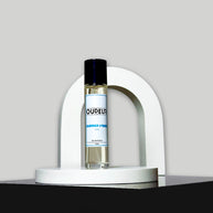 A bottle of perfume displayed on a white stand with a curved top, the liquid is clear and the cap is black. The label reads 'DUPEUR'.