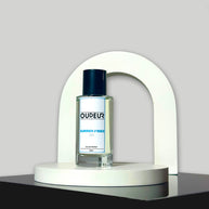 A bottle of perfume displayed on a white stand with a curved top, the liquid is clear and the cap is black. The label reads 'DUPEUR'.
