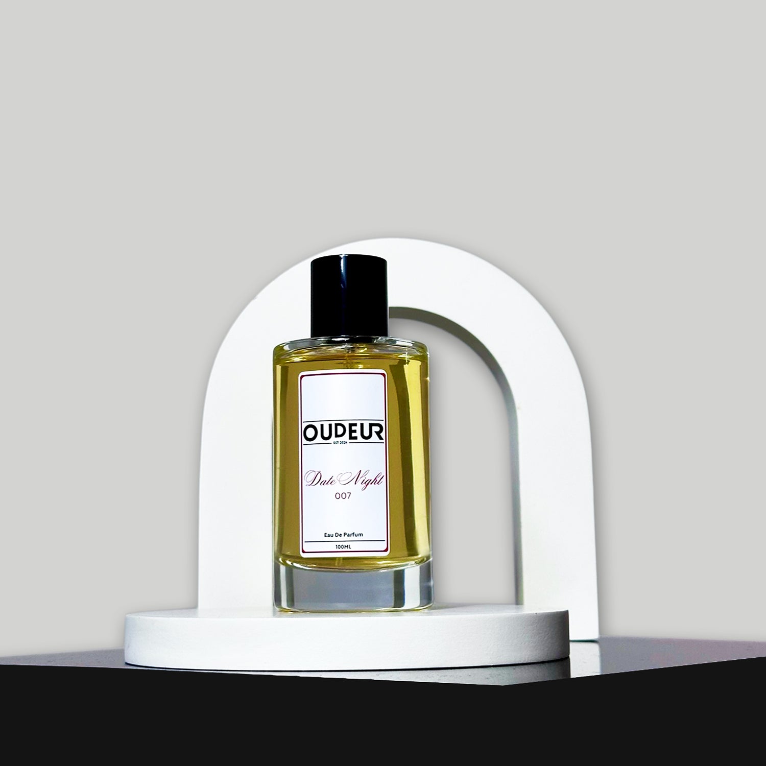 A bottle of perfume with a label that reads 'OUDENA - 007 Inspired by LV Ombre Nomade', placed on a white stand against a neutral background.