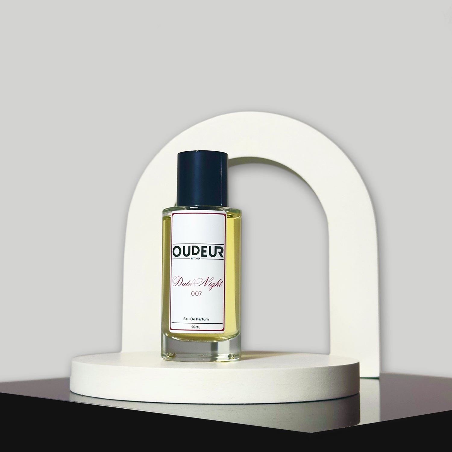 A bottle of perfume with a label that reads 'OUDENA - 007 Inspired by LV Ombre Nomade', placed on a white stand against a neutral background.