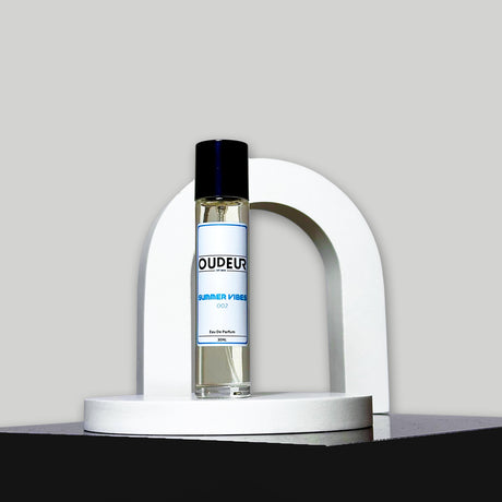 A bottle of 'Inspired by PDM Delina Exclusif' perfume by Parfums de Marly, placed on a white curved stand against a grey background.