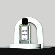 A bottle of unisex fragrance named 'OUDEUR' displayed on a white stand against a neutral background.