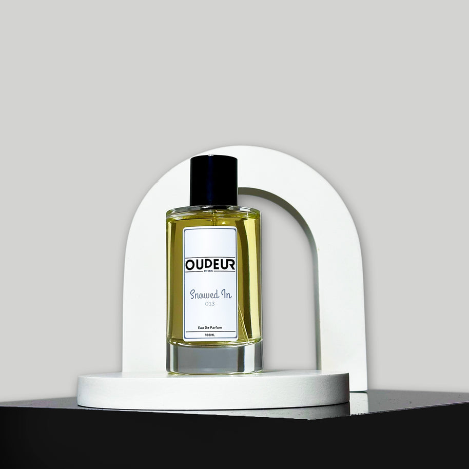 A bottle of perfume with a label that reads 'OUD EAU', placed on a white stand, with a white background.