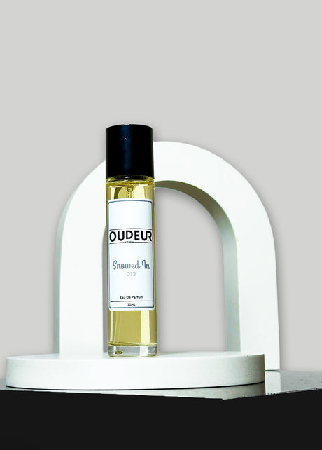 A bottle of perfume with a label that reads 'OUD EAU', placed on a white stand, with a white background.