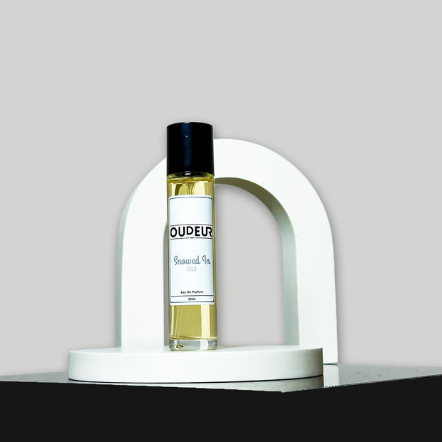 A bottle of perfume with a label that reads 'OUD EAU', placed on a white stand, with a white background.