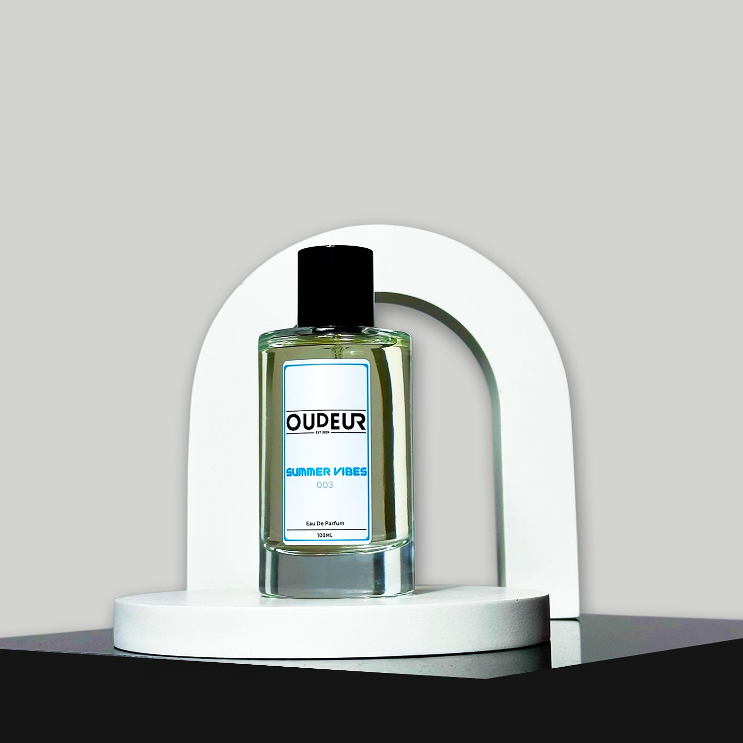 A bottle of perfume displayed on a white stand with a modern design, against a grey background.