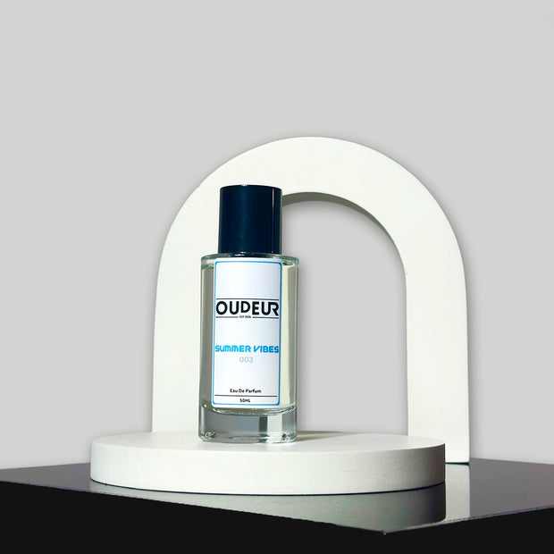 A bottle of perfume displayed on a white stand with a modern design, against a grey background.